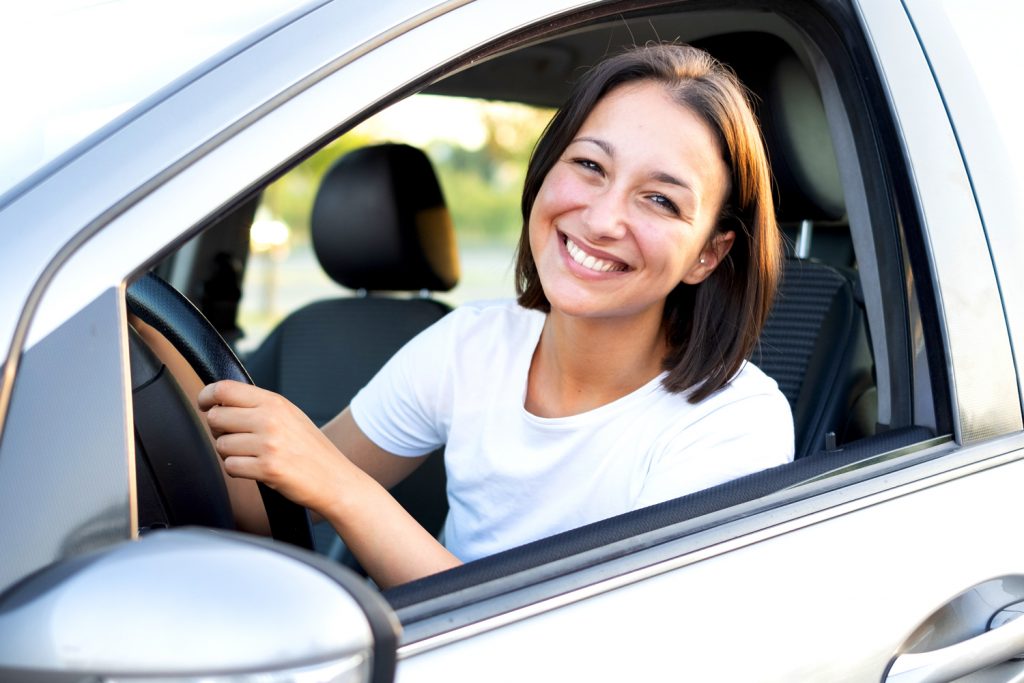 Freundlich lächelnde ambulante Pflegekraft in ihrem Auto.