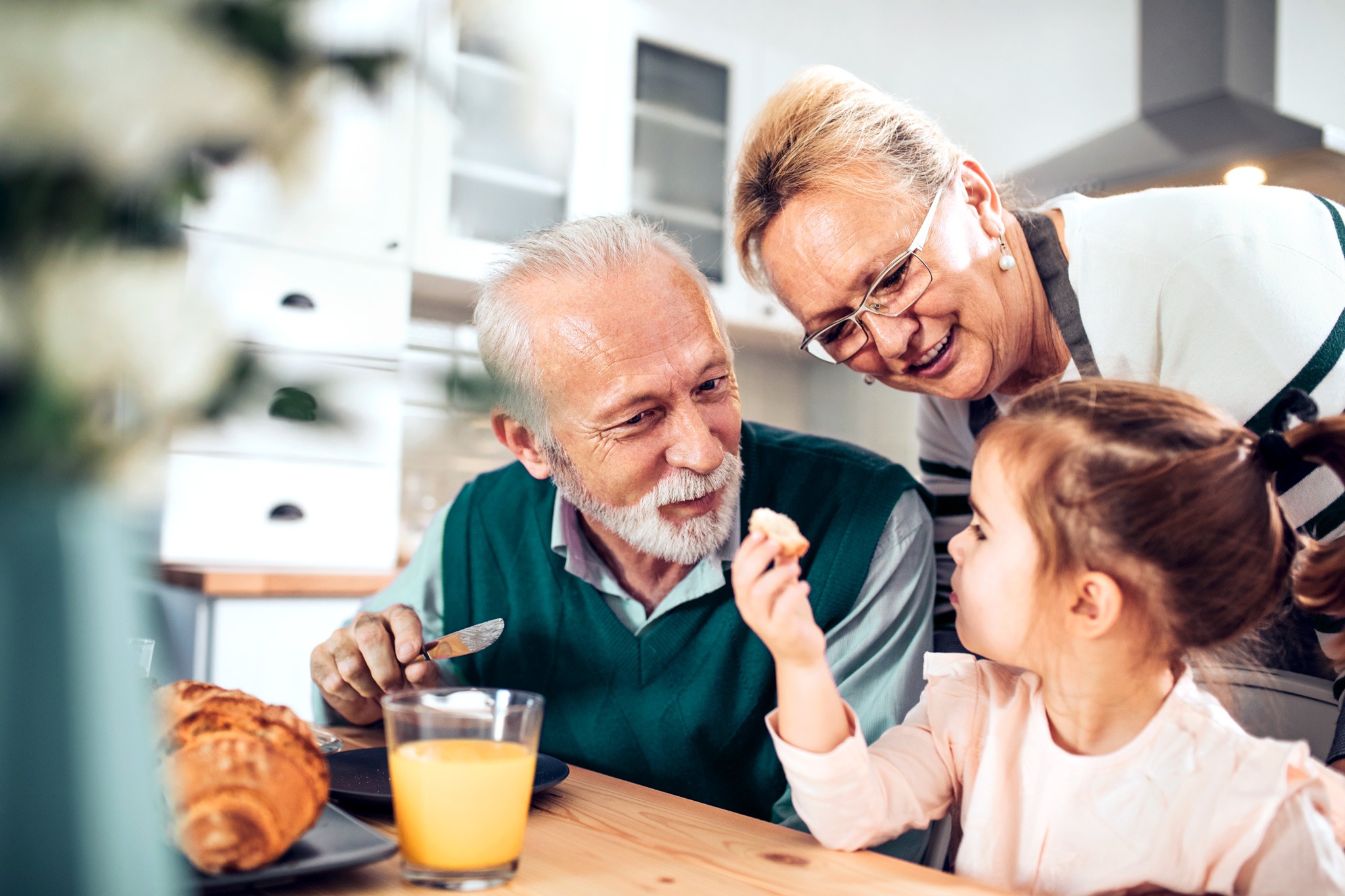 Ein Kind sitzt am Frühstückstisch mit seinen Großeltern.